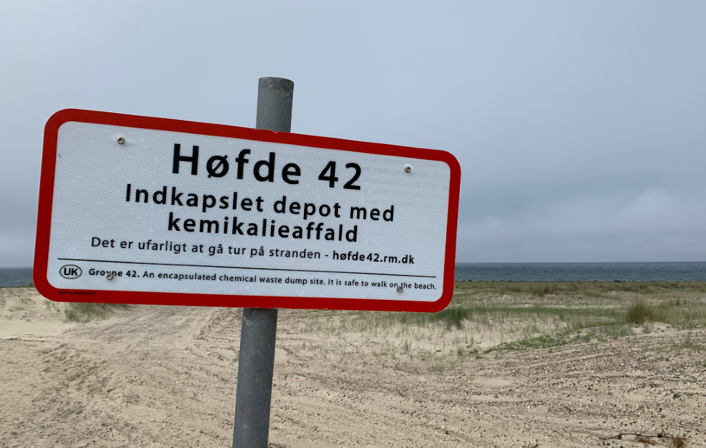 Foto af skiltet på stranden ved Høfde 42 med teksten "Indkapslet depot med kemikalieaffald".