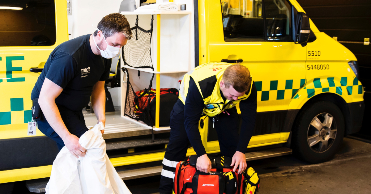 Kenneth og Christian trækker i værnemidler, før de skal ind til en patient, hvor der er mistanke om covid-19. Foto: Hans Christian Strickert