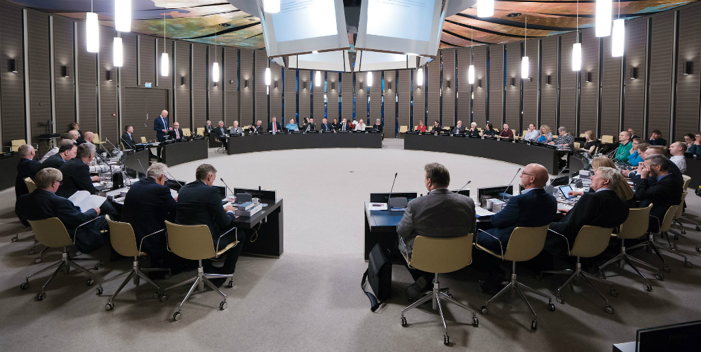 Politicians sitting in a circular room having ameeting of The Regional Council