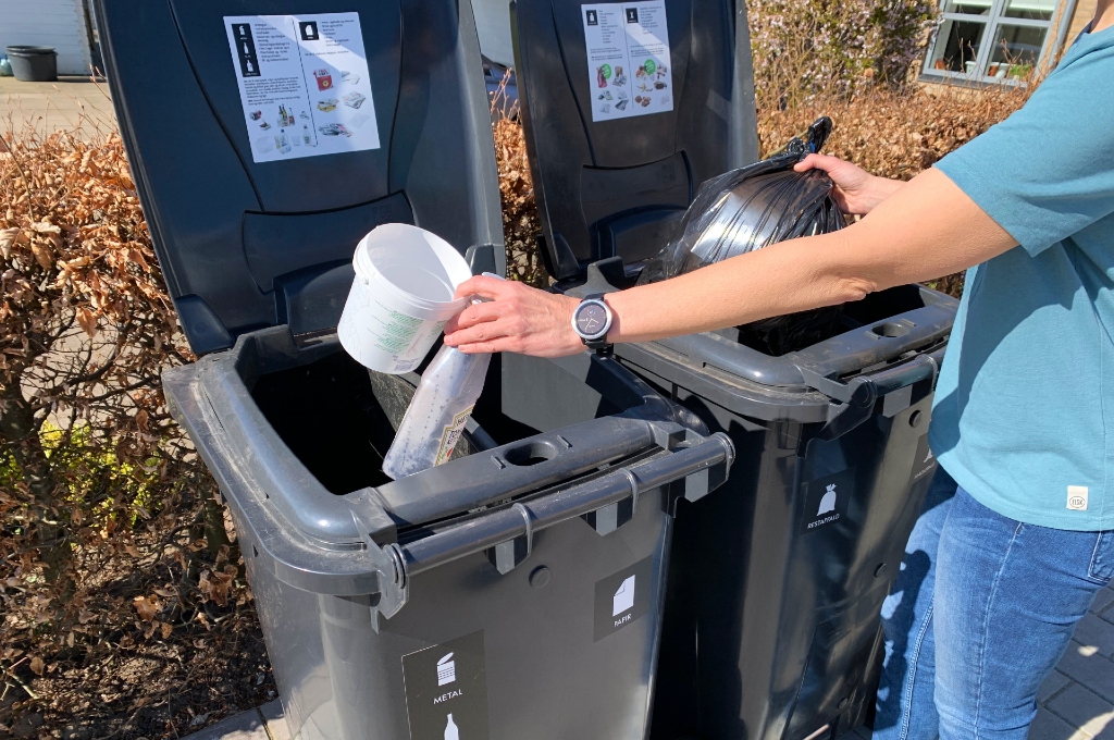 Foto af affald der sorteres i fire fraktioner i to husholdningsbeholdere i Danmark.